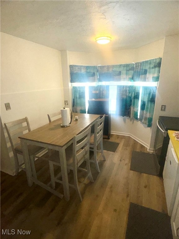 dining room featuring a textured ceiling and dark hardwood / wood-style flooring