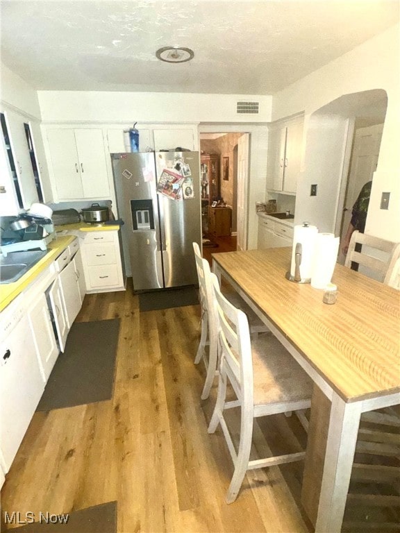 kitchen featuring sink, white cabinetry, stainless steel refrigerator with ice dispenser, and light hardwood / wood-style flooring