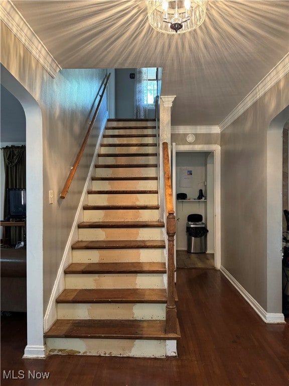 staircase featuring hardwood / wood-style flooring, ornamental molding, and a chandelier