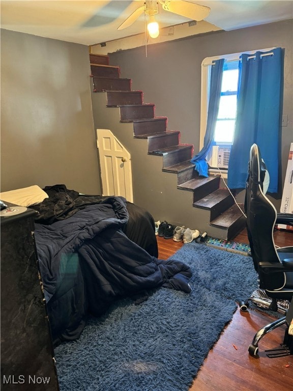 bedroom featuring cooling unit, hardwood / wood-style flooring, and ceiling fan