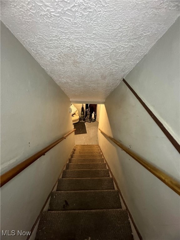 stairs featuring a textured ceiling