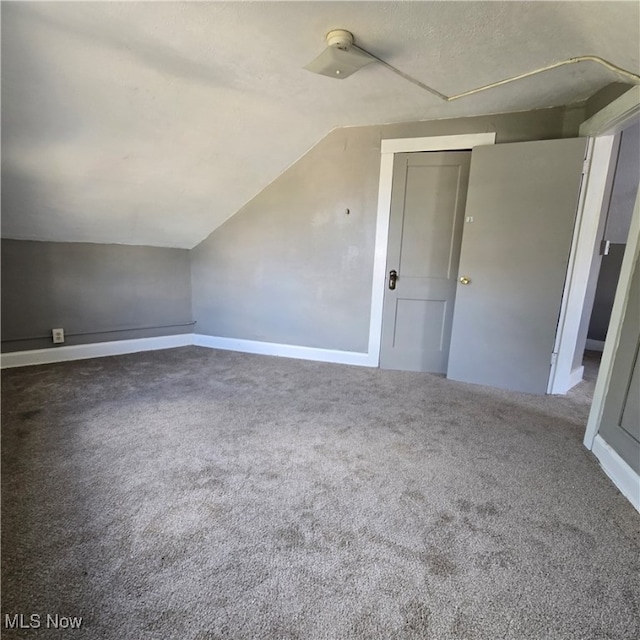 bonus room with lofted ceiling and carpet flooring