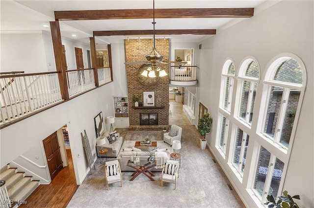 living room with a towering ceiling, beamed ceiling, a fireplace, and hardwood / wood-style floors