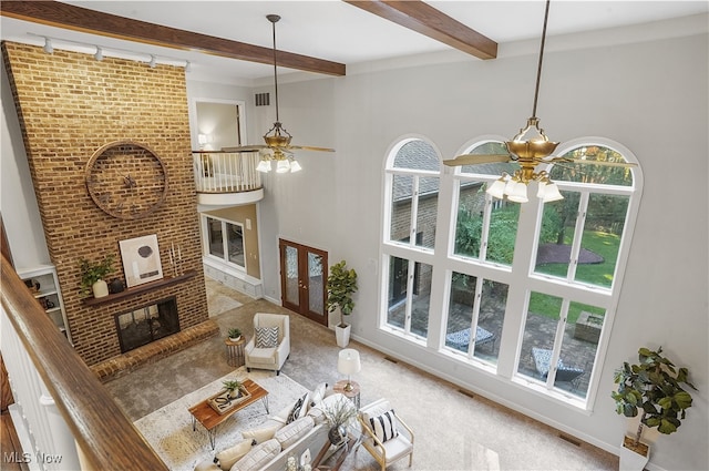 carpeted living room with beam ceiling, a fireplace, rail lighting, and ceiling fan