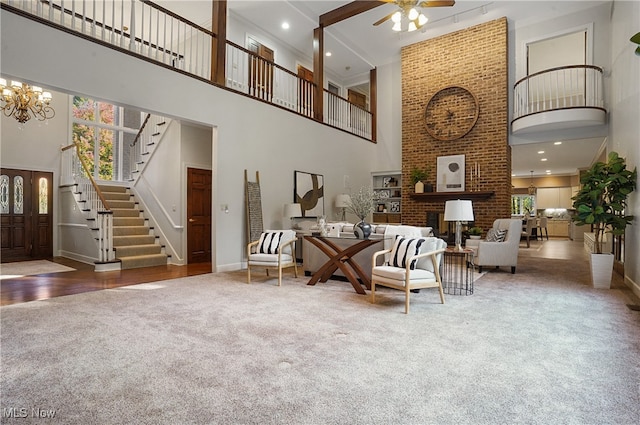 interior space featuring a high ceiling, a brick fireplace, and ceiling fan with notable chandelier