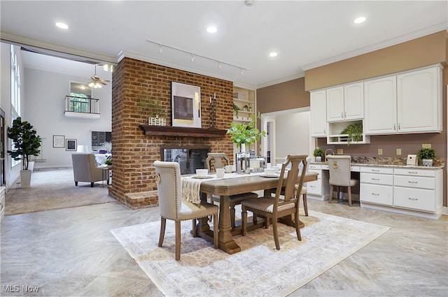 carpeted dining area with ornamental molding, ceiling fan, a fireplace, and rail lighting