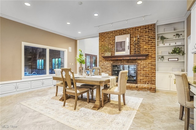 dining area featuring ornamental molding, built in shelves, a fireplace, and rail lighting