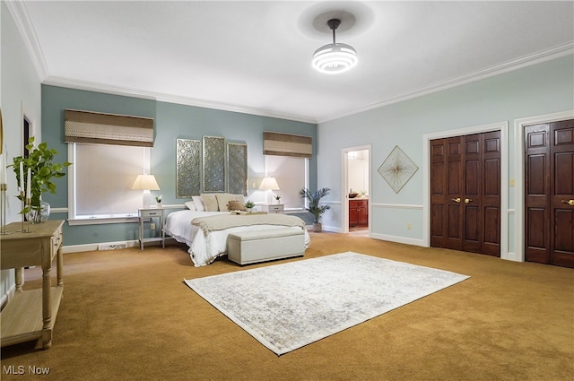 bedroom featuring connected bathroom, crown molding, multiple closets, and carpet flooring