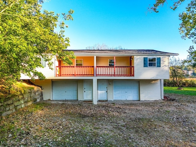 rear view of property featuring a balcony and a garage