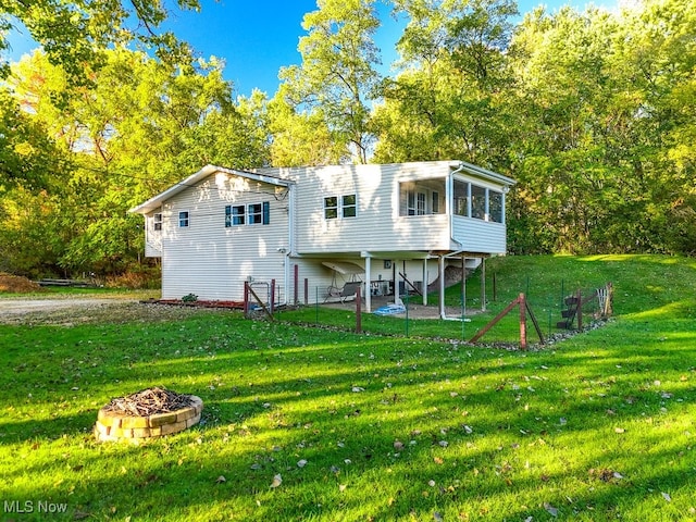 rear view of property with an outdoor fire pit, a yard, and a patio