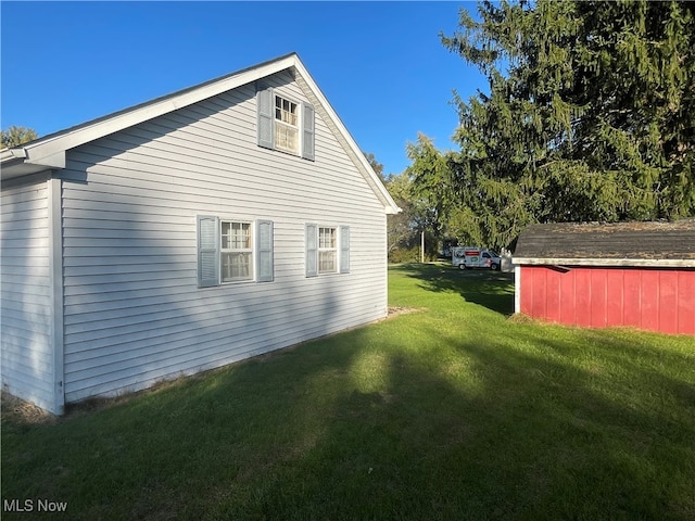 view of side of property with a lawn and a shed