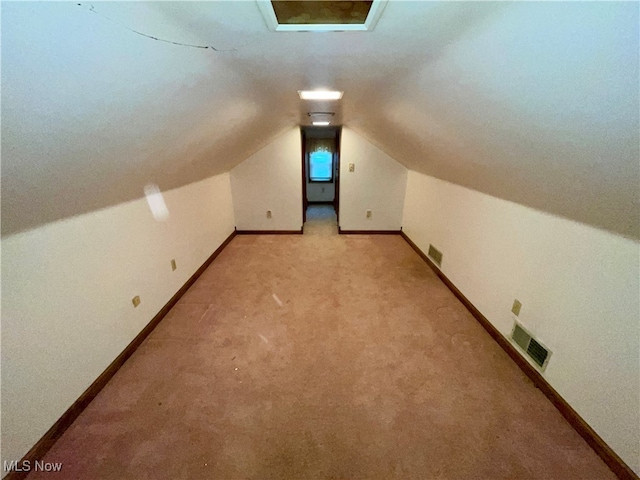 additional living space featuring lofted ceiling with skylight and light carpet