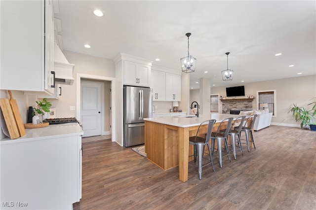 kitchen featuring white cabinetry, stainless steel fridge, a kitchen island with sink, and dark hardwood / wood-style floors