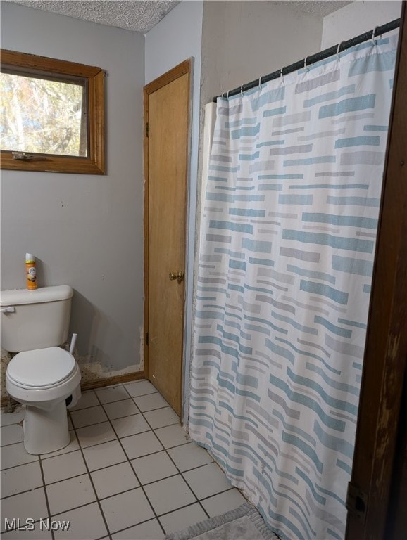 bathroom featuring tile patterned floors, a shower with shower curtain, a textured ceiling, and toilet