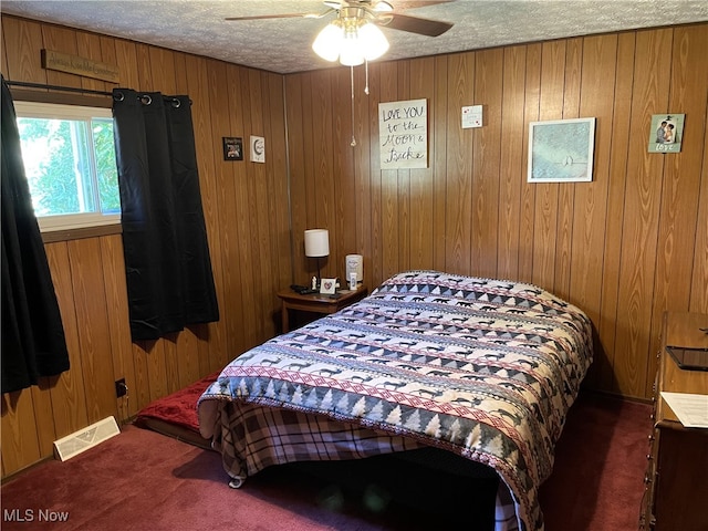 bedroom with dark colored carpet, a textured ceiling, wooden walls, and ceiling fan