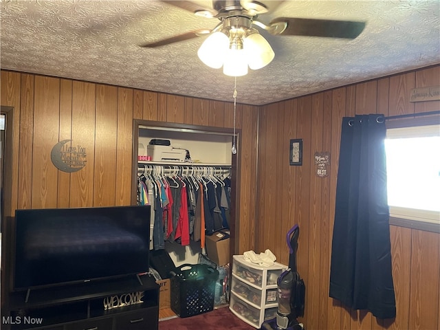 interior space with a closet, ceiling fan, and wood walls