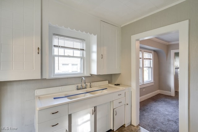 kitchen with ornamental molding, sink, white cabinetry, and carpet floors