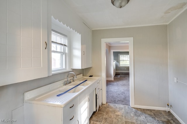 kitchen featuring a wealth of natural light, ornamental molding, sink, and white cabinets