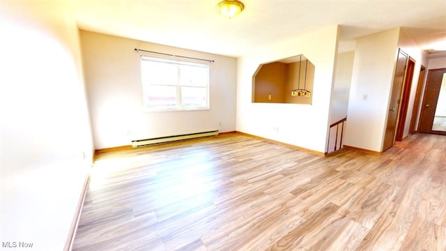 empty room featuring a baseboard radiator and light hardwood / wood-style flooring