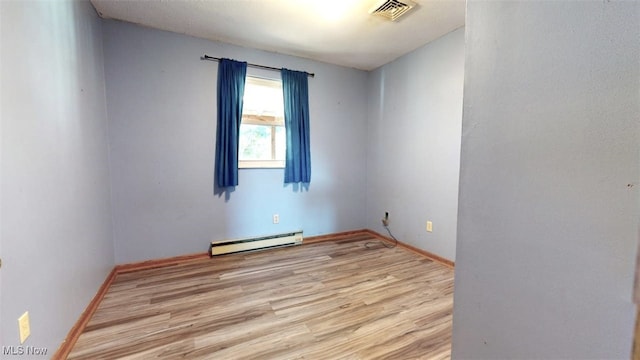 empty room with baseboard heating and light hardwood / wood-style flooring