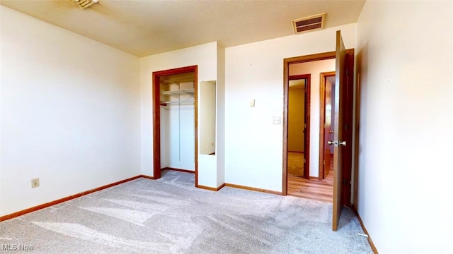 unfurnished bedroom featuring light carpet and a closet