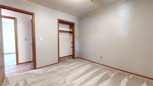 unfurnished bedroom with light carpet, a textured ceiling, and a closet