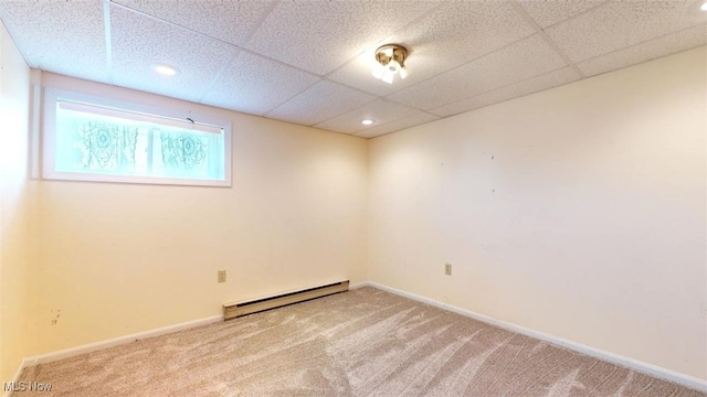 unfurnished room featuring a baseboard heating unit, a paneled ceiling, and carpet flooring