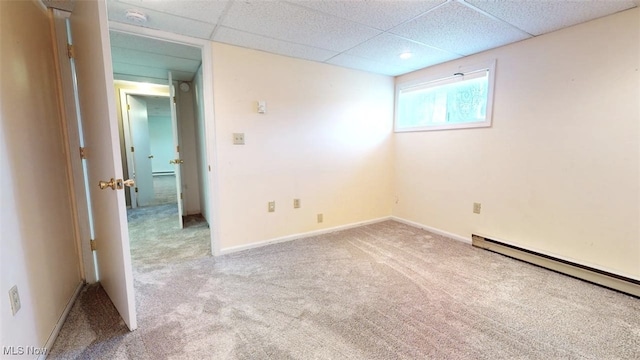 carpeted spare room featuring a baseboard radiator and a drop ceiling