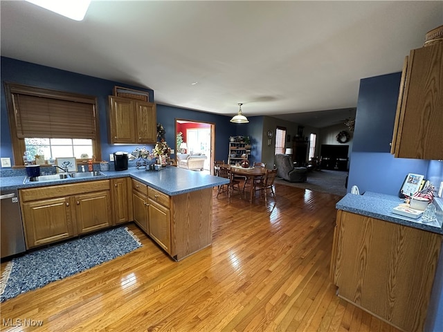 kitchen with sink, dishwasher, kitchen peninsula, light hardwood / wood-style floors, and pendant lighting