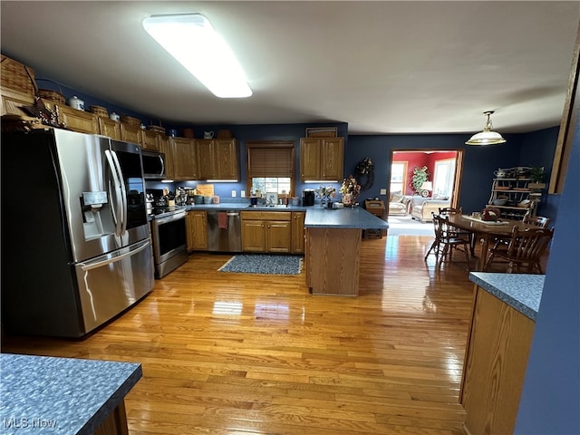 kitchen featuring sink, pendant lighting, stainless steel appliances, and light hardwood / wood-style floors