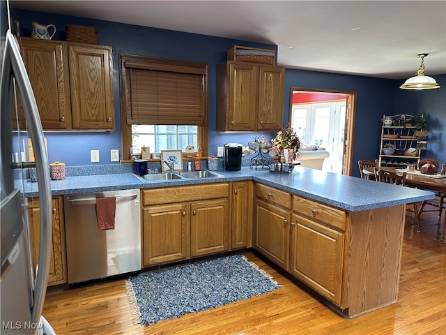 kitchen featuring sink, hanging light fixtures, stainless steel appliances, and light hardwood / wood-style floors