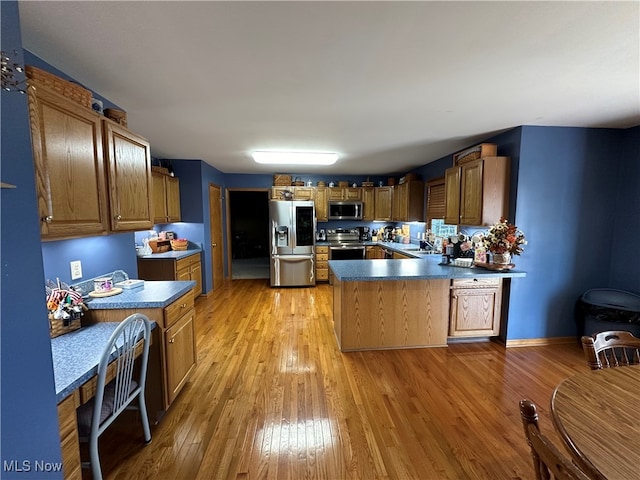 kitchen featuring sink, kitchen peninsula, stainless steel appliances, and light hardwood / wood-style floors