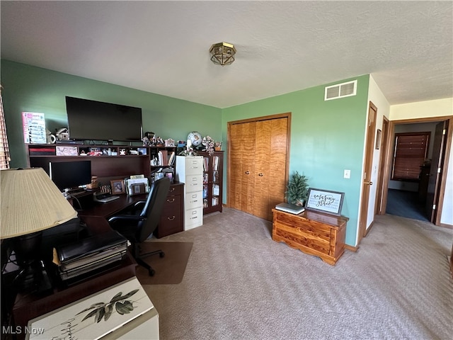 carpeted home office featuring a textured ceiling