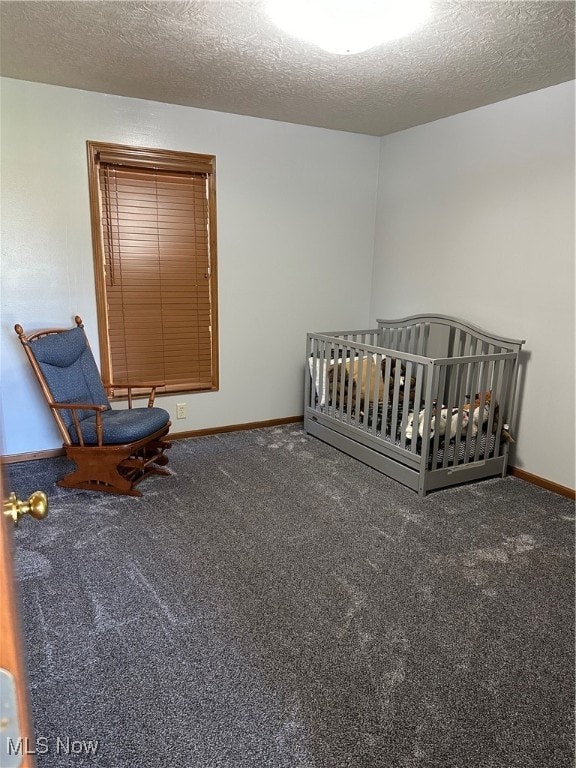 unfurnished bedroom featuring a textured ceiling, a crib, and carpet flooring