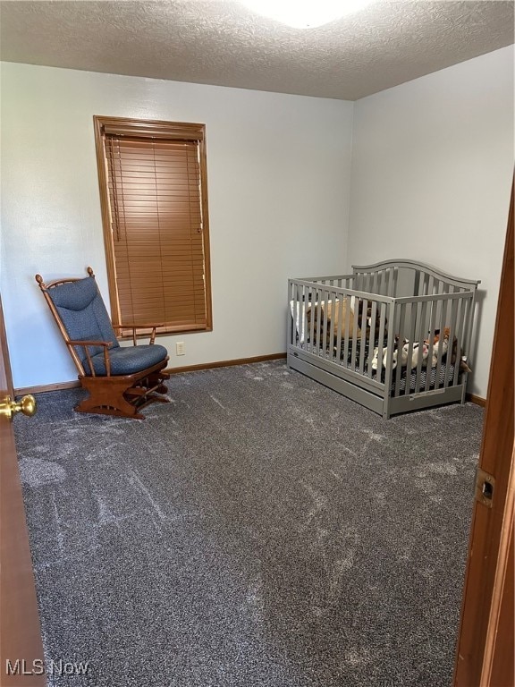 carpeted bedroom with a textured ceiling and a nursery area