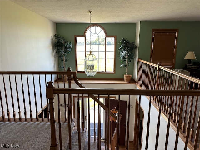 stairs featuring a notable chandelier, carpet flooring, and a textured ceiling