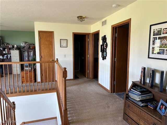 hall with carpet floors and a textured ceiling