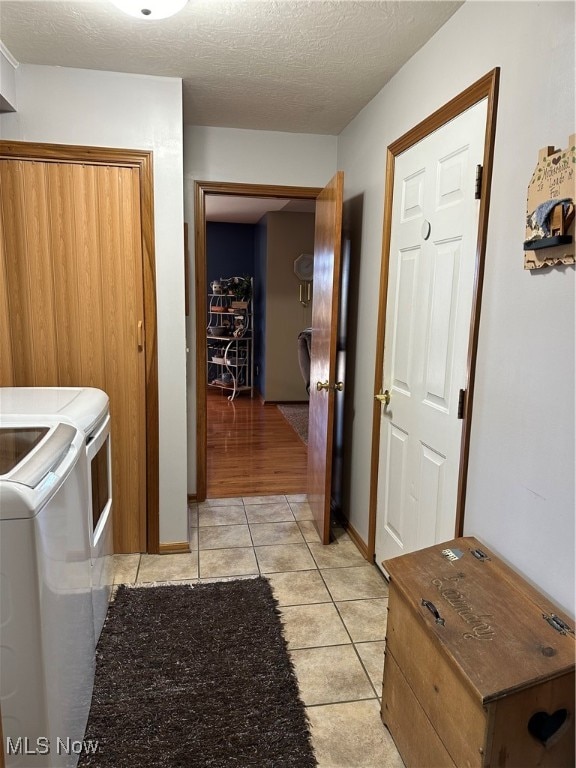 laundry room featuring a textured ceiling, separate washer and dryer, and light tile patterned floors