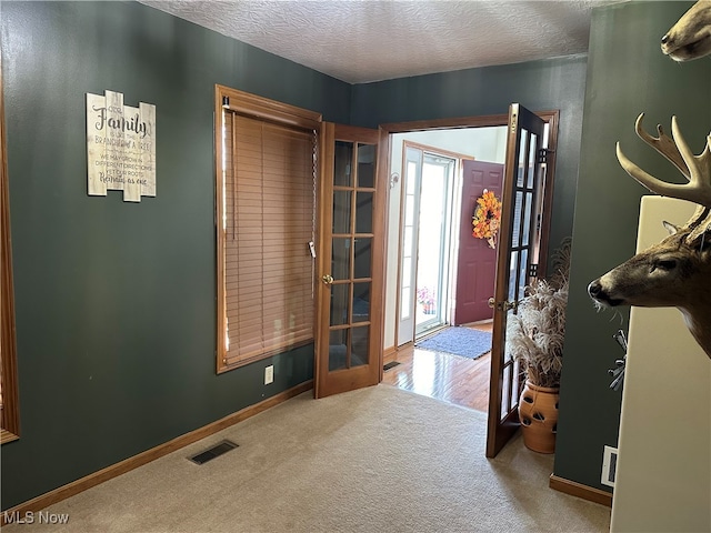 carpeted foyer entrance featuring french doors and a textured ceiling