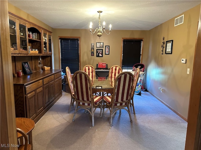 carpeted dining area featuring a notable chandelier and a textured ceiling