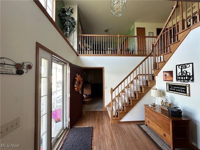 entryway with wood-type flooring and a towering ceiling