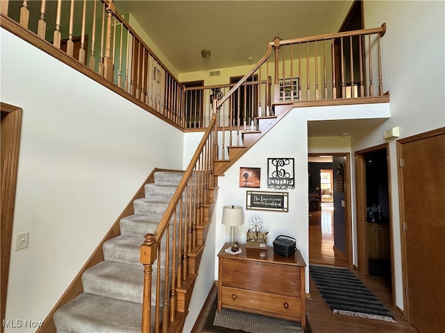 staircase with hardwood / wood-style flooring and a towering ceiling