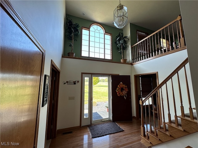 foyer entrance featuring an inviting chandelier, hardwood / wood-style floors, and a high ceiling