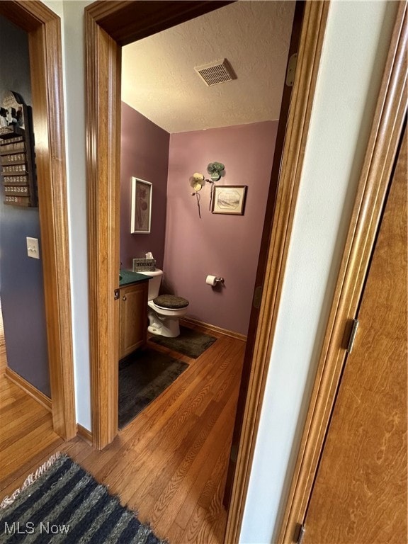 bathroom featuring vanity, toilet, a textured ceiling, and hardwood / wood-style floors