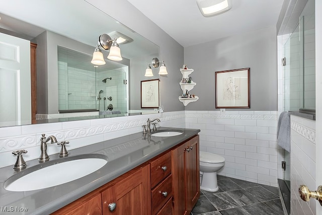 bathroom featuring tile walls, vanity, a shower with shower door, and toilet