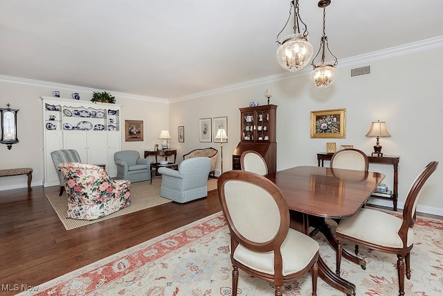 dining room with hardwood / wood-style flooring, ornamental molding, and an inviting chandelier