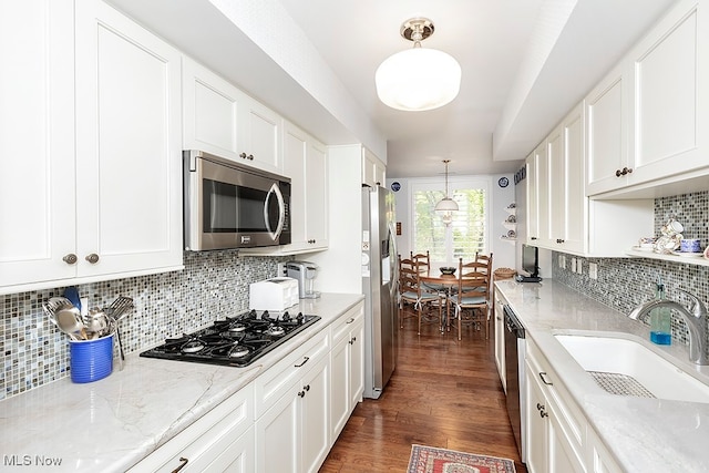 kitchen with appliances with stainless steel finishes, dark hardwood / wood-style flooring, white cabinets, and pendant lighting