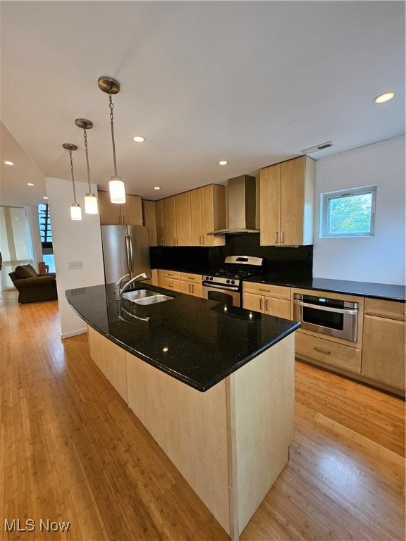 kitchen featuring a kitchen island with sink, wall chimney exhaust hood, light hardwood / wood-style flooring, stainless steel appliances, and sink