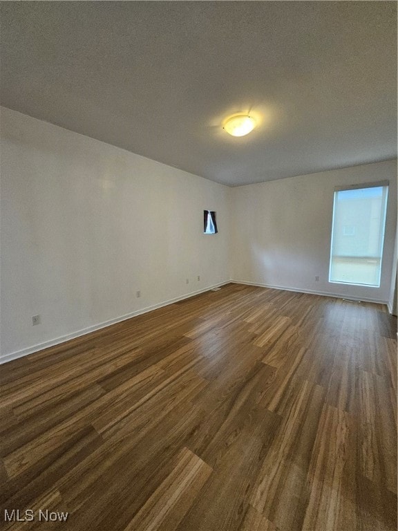 empty room with a textured ceiling and dark wood-type flooring