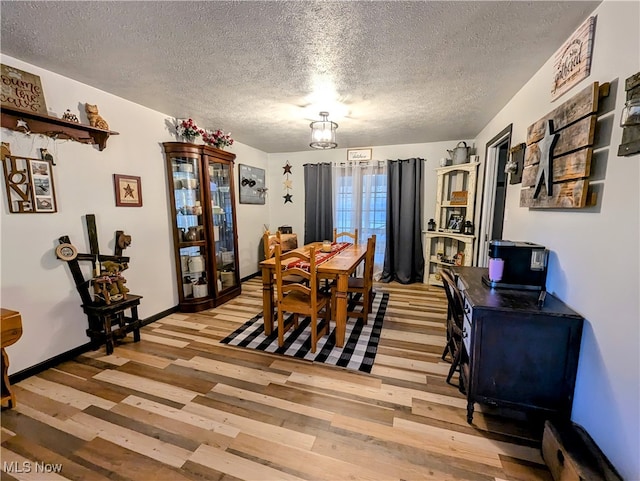 dining area featuring a textured ceiling and light hardwood / wood-style flooring